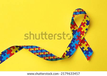 World Autism Awareness Day. Colorful puzzle ribbon on yellow background, top view Royalty-Free Stock Photo #2179633457