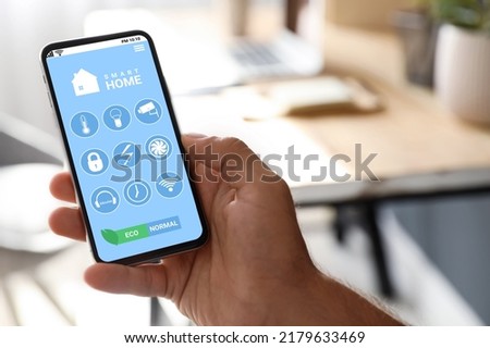 Man using Smart Home app on mobile phone indoors, closeup