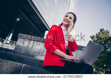 Photo of joy smile marketer aged lady sit modern financial center use netbook speak gadget employers employee outdoors