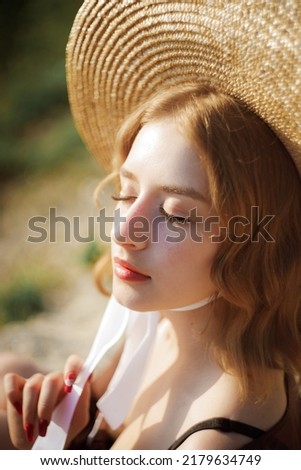 Portrait of cute girl in straw hat with closed eyes, soft background