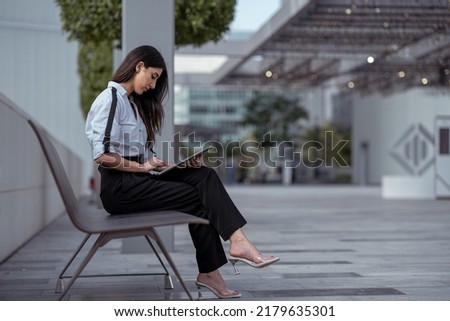 Happy business woman using laptop or tablet wearing professional in corporate background. Arab or Indian businesswoman excited on screen Royalty-Free Stock Photo #2179635301