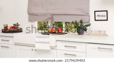 White kitchen interior with double bowl sink in front of window and fresh fruits