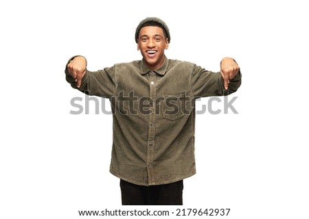 Look, advertise below. Cheerful guy pointing down place for commercial idea, looking at the camera with shocked face. Studio shot isolated on white background