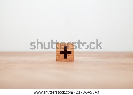 + Character. plus. Addition. gain. Written on a wooden block. Black letters. Wooden table background.