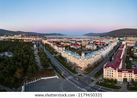 Aerial view of a seaside town. Top view of the streets and buildings. In the distance the sea bay and mountains. Beautiful morning cityscape. City of Magadan, Magadan region, Far East of Russia. Royalty-Free Stock Photo #2179650331
