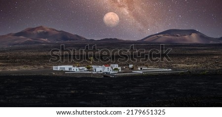 Amazing nocturnal panoramic landscape of volcano craters in Timanfaya national park. Full moon over La Gueria, Lanzarote island, Canary islans, Spain. Artistic night sky picture
