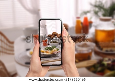 Woman taking picture of different dishes served on wooden table, closeup