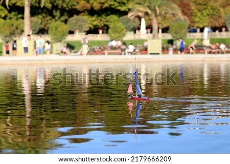Photo on theme of lonely toy boat with sail sailing fast on clear water