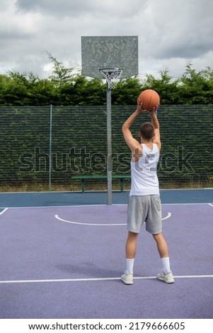 A Nineteen Year Old Teenage Boy Shooting A Hoop in A Basketball Court in A Public Park