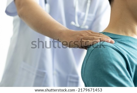 Doctor is diagnosing a male patient's neck and shoulder pain.