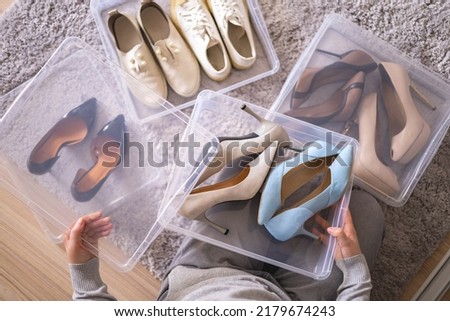 Female hands pack shoes on heels into plastic box home wardrobe storage method organization top view closeup. Woman housewife during general cleaning many footwear packing neatly filling cabinet Royalty-Free Stock Photo #2179674243