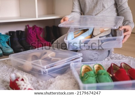 Female hands pack shoes on heels into plastic box home wardrobe storage method organization top view closeup. Woman housewife during general cleaning many footwear packing neatly filling cabinet Royalty-Free Stock Photo #2179674247