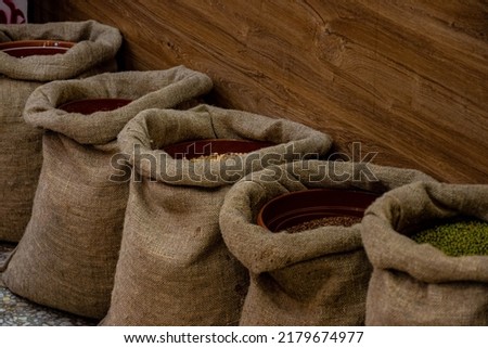 several gray coarse canvas bags with spices stand along the wall in the oriental bazaar Royalty-Free Stock Photo #2179674977