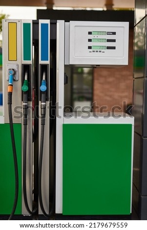 Modern green fuel dispenser with gas pump nozzles and displays with prices at filling station Royalty-Free Stock Photo #2179679559