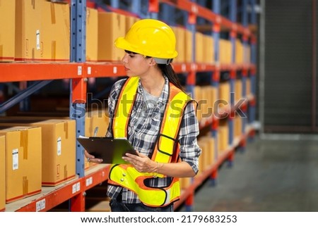 A women in charge of a large warehouse is checking the number of items in the warehouse that he is responsible for.