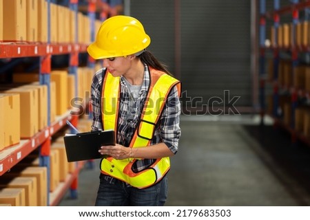 A women in charge of a large warehouse is checking the number of items in the warehouse that he is responsible for.