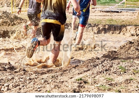 Group of participants in an obstacle course race running across a pool of water. Spartan race. Concept of hardness and effort Royalty-Free Stock Photo #2179698097