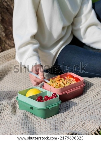 Lunch in the park, picnic.A person eats lunch from a plastic container. Lunch box with healthy foods, fruits  Royalty-Free Stock Photo #2179698325