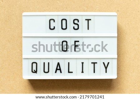Lightbox with word cost of quality on wood background