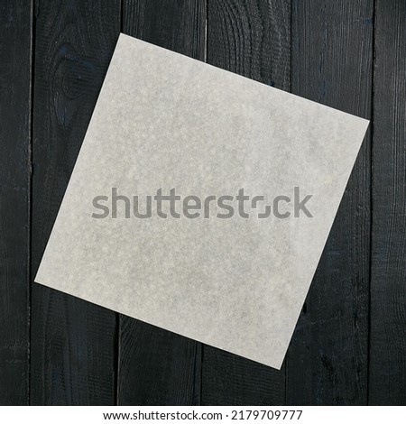 Vintage mock up with blank parchment on a black wooden background. Dark wooden background with copy space. Black wood with a piece of paper for design. Dark wooden background. Royalty-Free Stock Photo #2179709777
