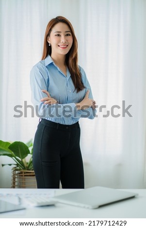 Successful Asian businesswoman smiling happily working on documents in the office vertical picture