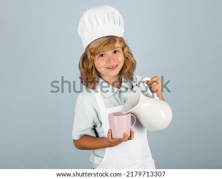 Milk for kids. Child chef isolated on blue. Funny little kid chef cook wearing uniform cook cap and apron cooked food in the kitchen.