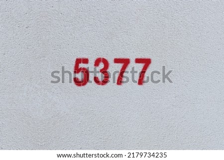 Red Number 5377 on the white wall. Spray paint.
