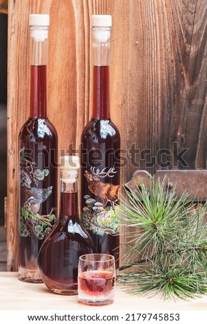 a glass and hand painted bottles fresh liquor from the swiss stone pine at a sunny july day with weathered wood board in the background