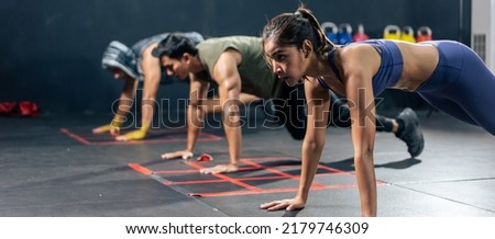 Group of young athlete people doing exercise together in fitness gym. Attractive sportsman and women working out raising legs up and spinning moving on the air for health care in fitness gym stadium. Royalty-Free Stock Photo #2179746309