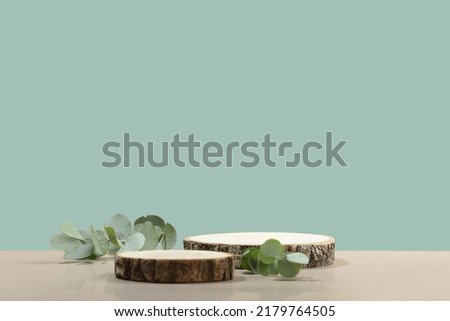 Minimal modern product display on neutral blue background. Wood slice podium and green leaves. Concept scene stage showcase for new product, promotion sale, banner, presentation, cosmetic Royalty-Free Stock Photo #2179764505