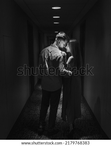 Young couple in love standing face to face in the corridor of the hotel. Black and white