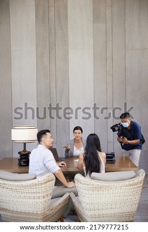 Professional male photographer filming, taking pictures of business or consulting meeting with agent in real estate office. Behind the scene in photography industry. Filming stock photography content