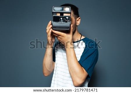 Studio portrait of young man photographer making photo with polaroid camera. Royalty-Free Stock Photo #2179781471