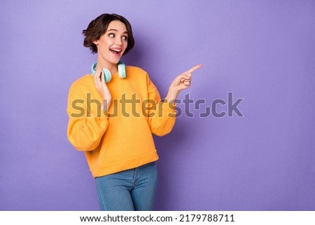 Portrait of excited cheerful girl look direct finger empty space proposition isolated on purple color background
