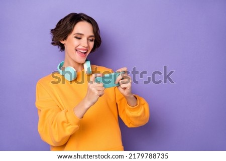 Photo of funky positive crazy girl enjoy playing video games hold telephone isolated on violet color background