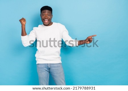 Photo of cheerful overjoyed young man promote product celebrate his victory isolated on blue color background