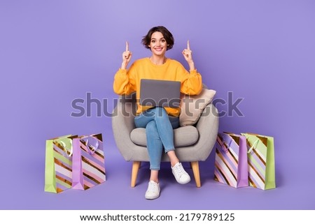 Portrait of beautiful trendy cheerful girl using laptop buying goods showing copy space ad isolated over violet lilac color background