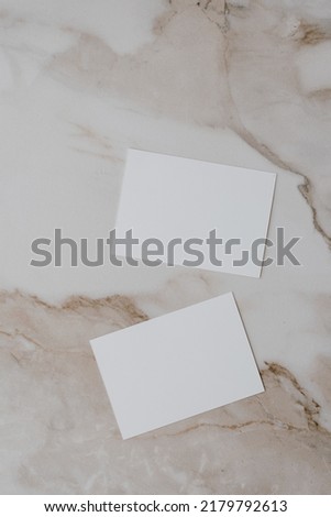 Flatlay of blank paper card on neutral beige marble background. Business template. Top view, flat lay minimalist aesthetic luxury bohemian business branding concept
