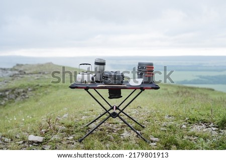 Equipment for camping kitchen, cooking in nature, a set of camping utensils, an iron kettle, a metal pot, a folding table, a thermo glass. High quality photo