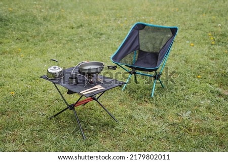 Camping furniture, compact equipment, camping equipment, camping utensils are on the table, a folding chair, a gas burner, a kettle. High quality photo