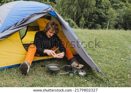 Fried scrambled eggs on a hike in a frying pan, a guy cooks in a tent, camping in nature, knife in hand, cooking on a gas burner, trekking. High quality photo