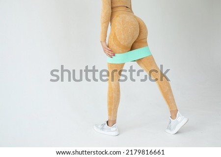 Fitness black woman doing exercise for glutes with resistance band on grey background. Athletic girl working out.