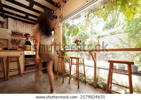 Blurred motion of young woman walking to coffeeshop counter to order morning coffee Royalty-Free Stock Photo #2179824631