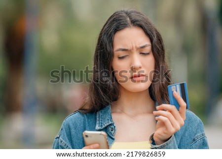 girl with mobile phone and credit card with expression of doubt or mistrust Royalty-Free Stock Photo #2179826859