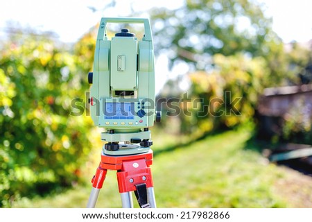 surveying equipment with transit total station and theodolite with garden background