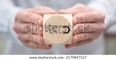 Hand holding a wooden cube with symbol of investors attraction concept Royalty-Free Stock Photo #2179847527