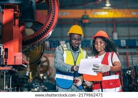 Two professional engineer,worker,technician use clipboard discuss work, walk in steel metal manufacture factory plant industry. Black African American man and woman wear hard hat check quality machine Royalty-Free Stock Photo #2179862471