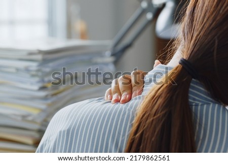 Tired Asian office employee massaging neck and shoulder muscles fatigued from using laptop computer for a long time, office syndrome concept Royalty-Free Stock Photo #2179862561