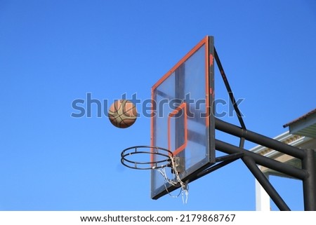Basketball and hoop under a blue sky