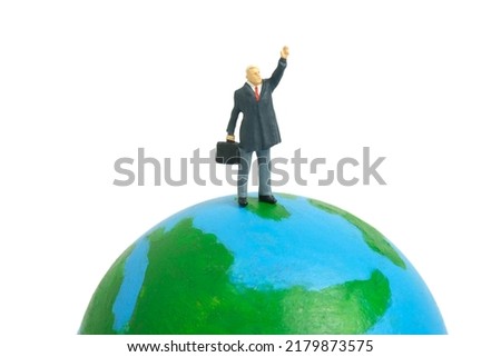 Miniature people toy figure photography. Rule the world concept. A businessman standing above globe while raise his hand. Isolated on white background. Image photo